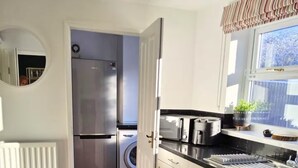 A compact kitchen with a refrigerator, washing machine, and a sink.