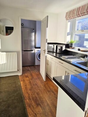 Una cocina compacta equipada con refrigerador, lavadora y pileta.