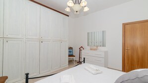 Ein Schlafzimmer mit Bett, weißem Wandschrank, Holztür und Spiegel über dem Schminktisch.