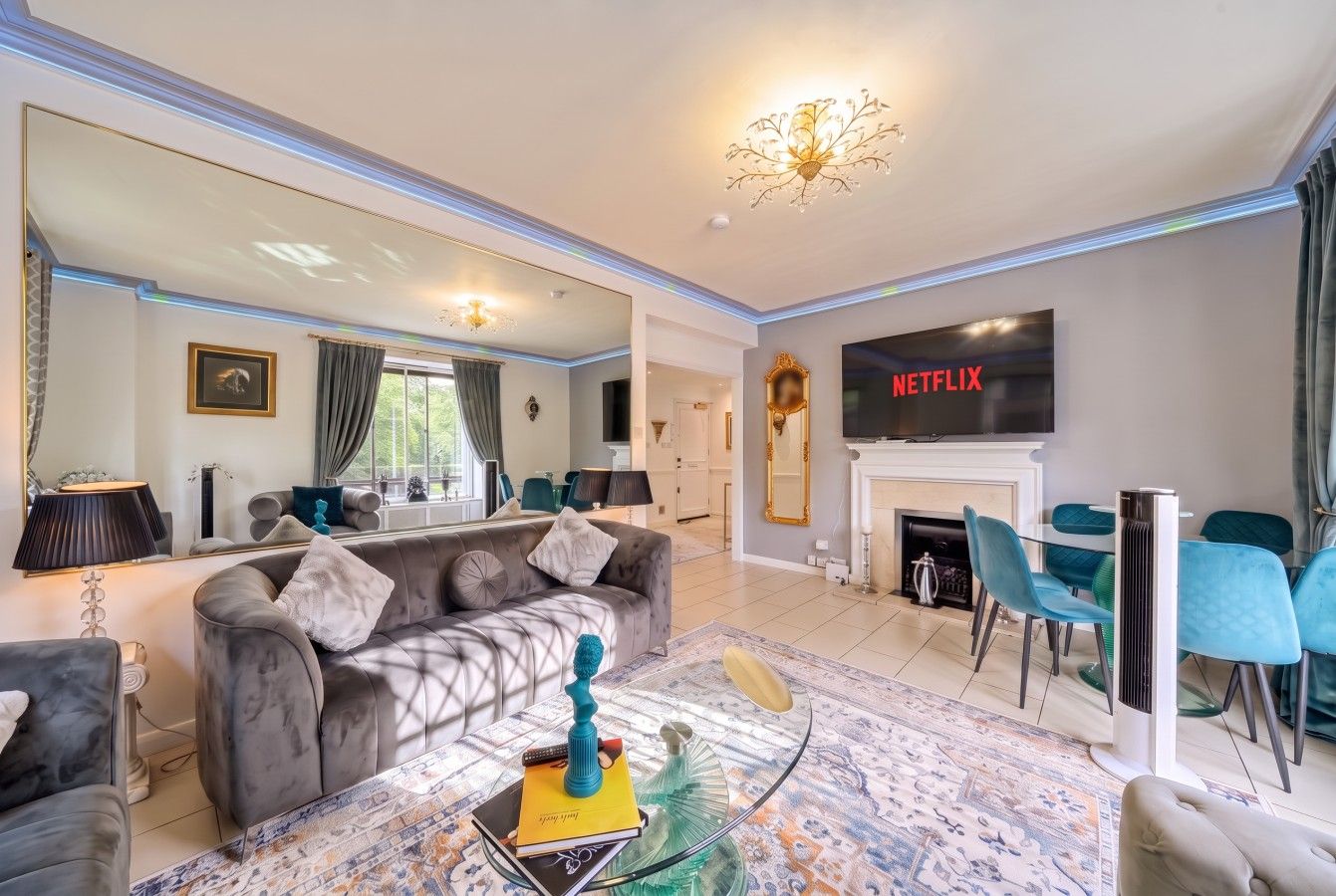 The grey velvet sofa faces the wall-mounted TV above the fireplace