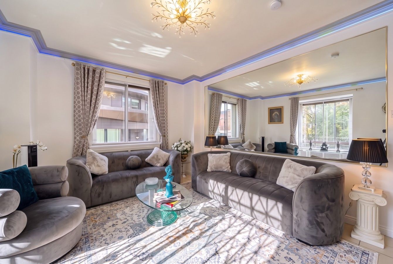 A living room with two sofas, a glass coffee table, and a large mirror.