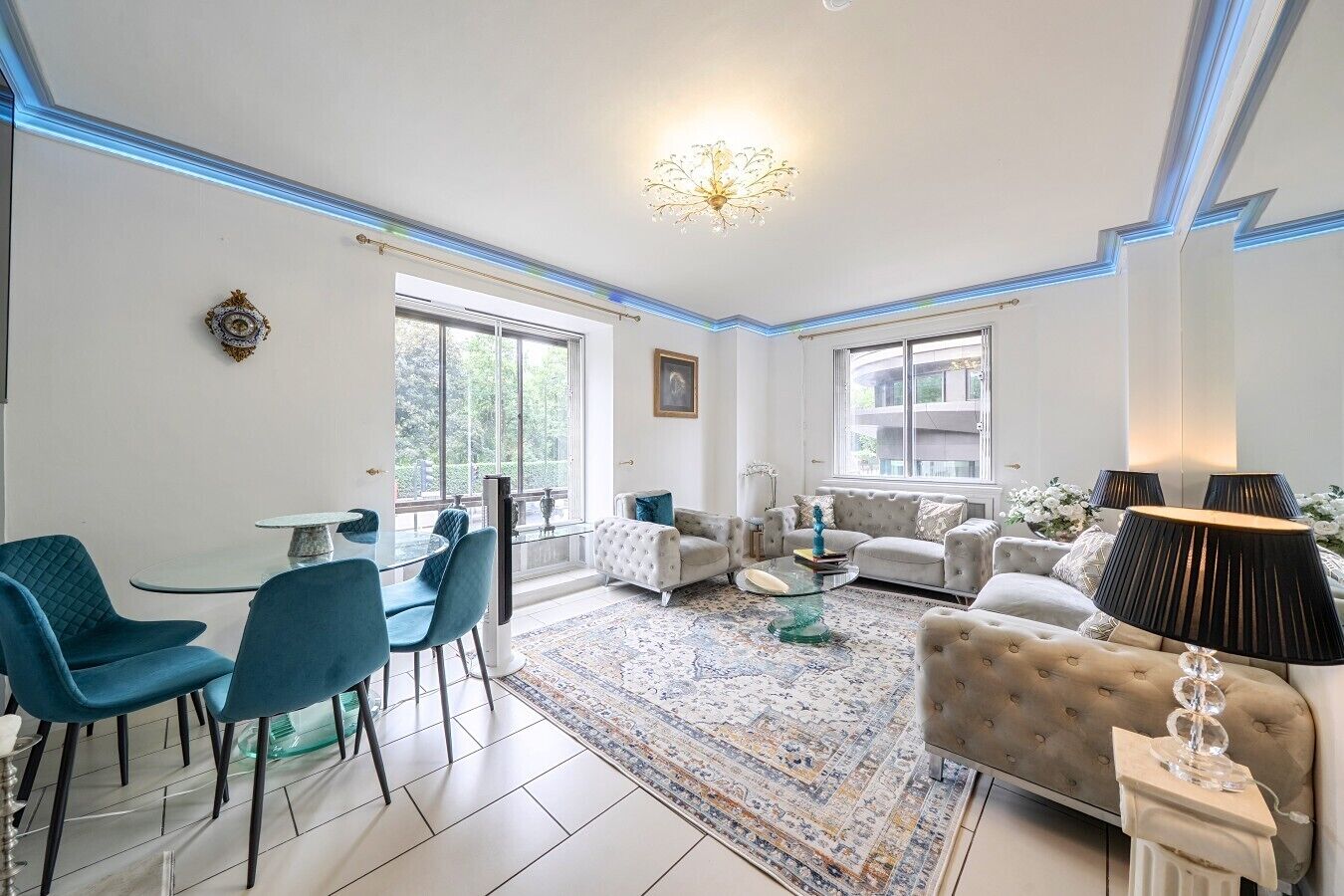 A modern living room with a dining area, large windows, and a chandelier.