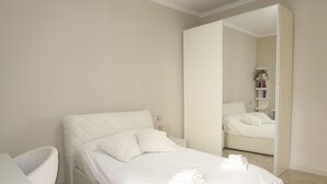 A modern bedroom with a large bed, a bedside table, a chair, and a mirror. - Empire home (Roma)