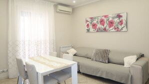 A living room with a dining table, chairs, a sofa, and a radiator. - Empire home (Roma)