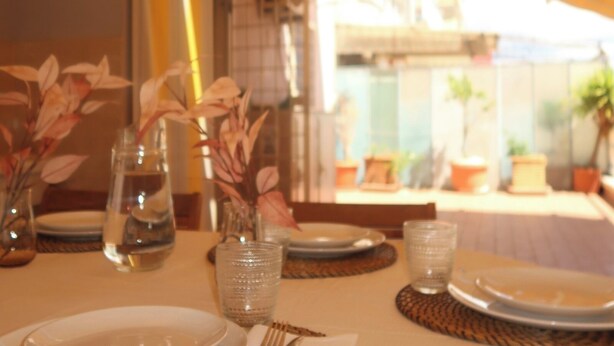 A table set for dining with clear glassware and a vase with dried flowers. - Empire home (Roma)