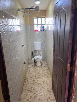 Ein schmales Badezimmer mit Toilette, einem Handtrockner und einem Fenster.