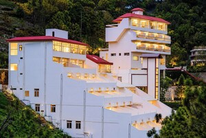 A modern multi-story hotel with a unique stepped design, large windows, and a red roof.