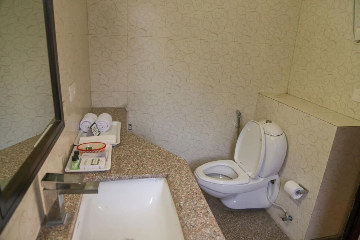 Un baño con lavamanos, inodoro y toallero con toallas.