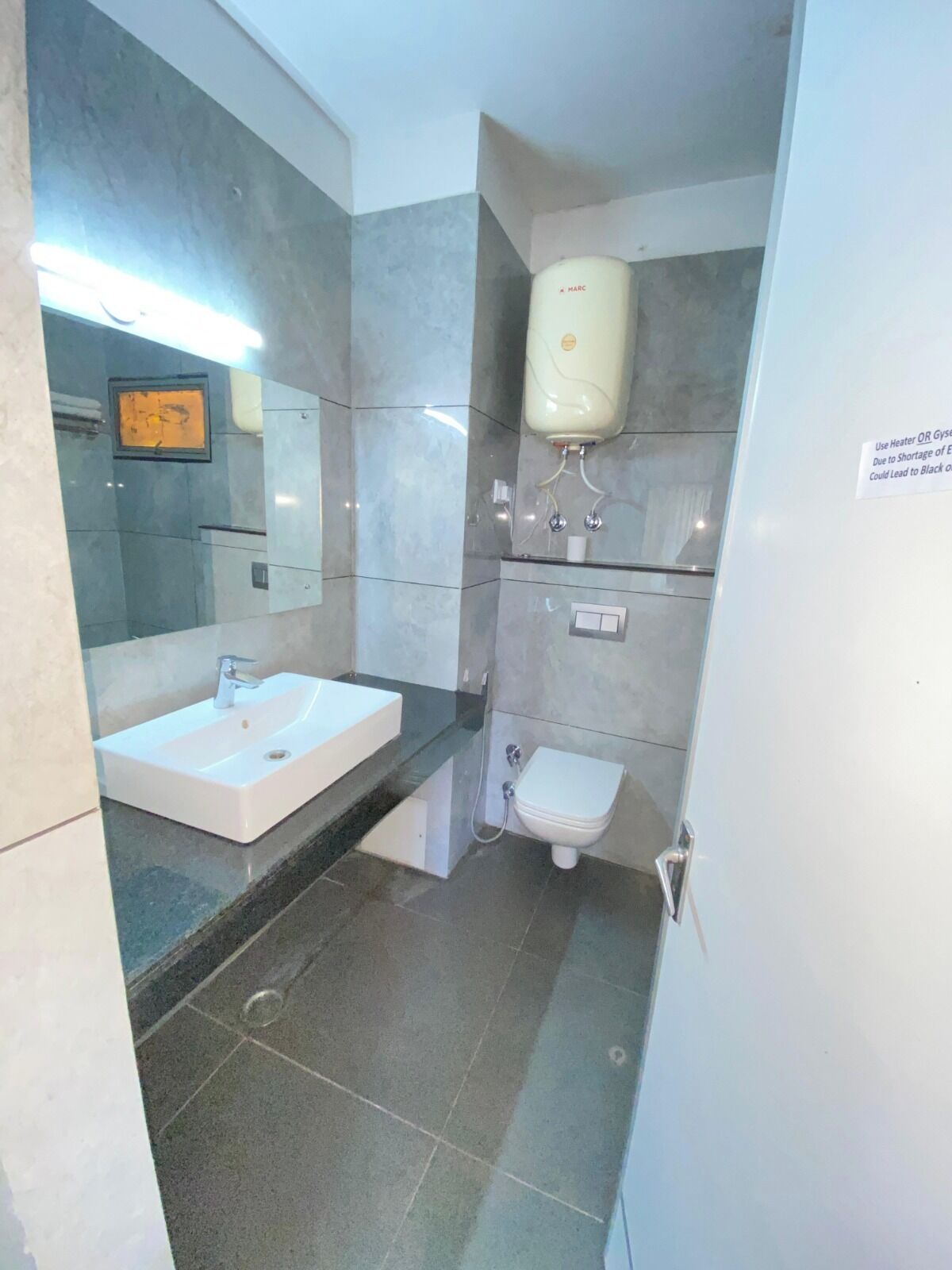 Une salle de bain équipée d’un lavabo, d’un miroir, de toilettes et d’un sèche-mains.