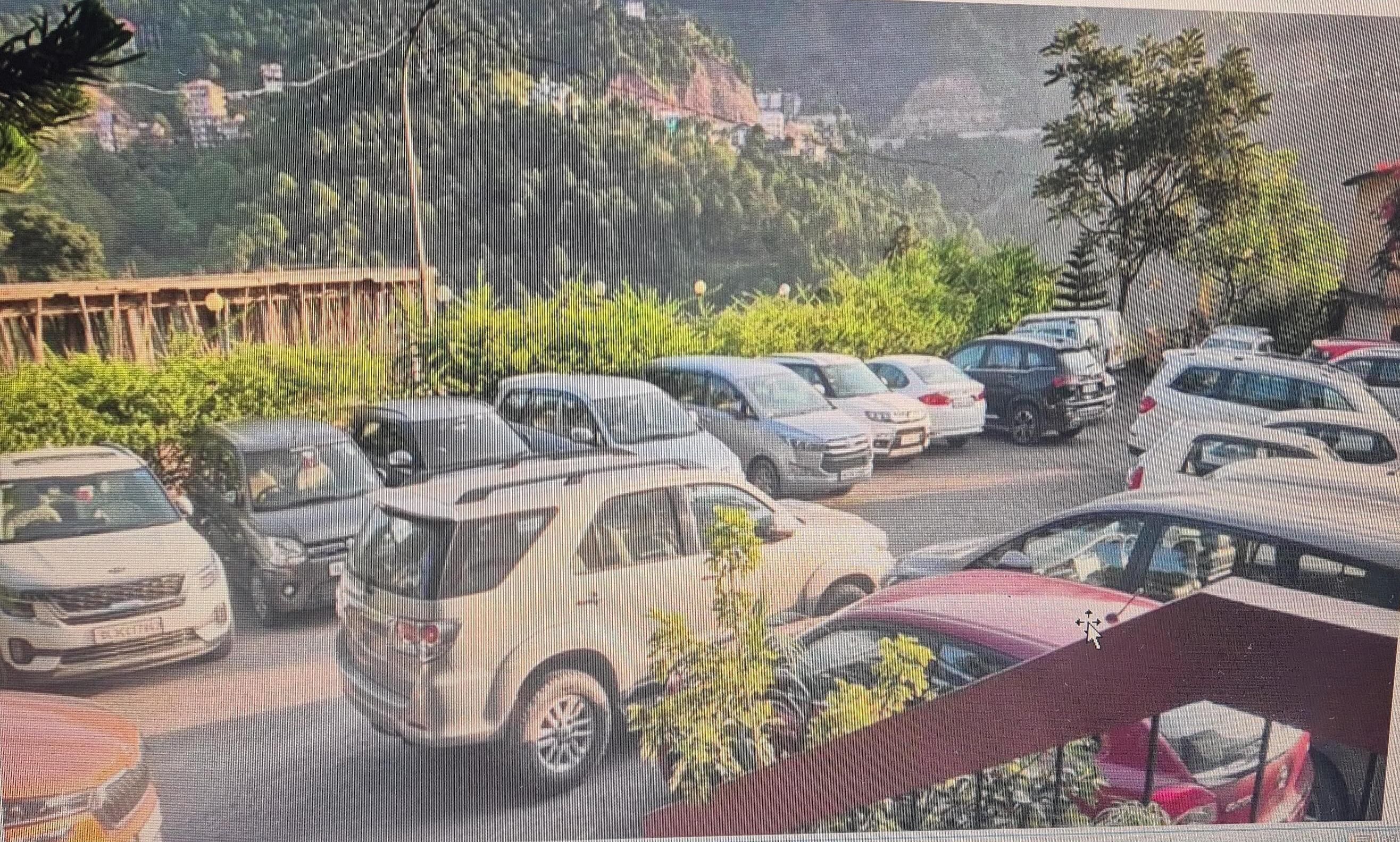 A parking lot with multiple cars and a few trees in the background.