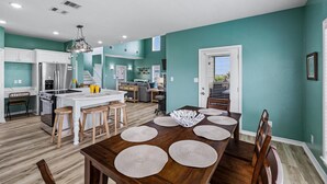 Una cocina moderna con armarios blancos, una isla central y taburetes de madera.