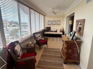 Ein Wohnzimmer mit einer Couch, zwei Sesseln, einer Holzkommode und einem Deckenventilator.