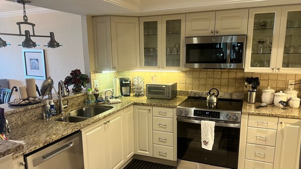 A modern kitchen with white cabinetry, stainless steel appliances, a microwave, and a gas stove. - 1200-505 Standard Plus (Siesta Key)