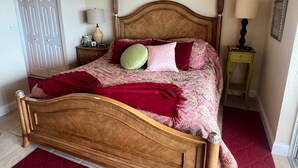 A bedroom with a wooden bed, a nightstand, a lamp, and a door. - 1200-505 Standard Plus (Siesta Key)