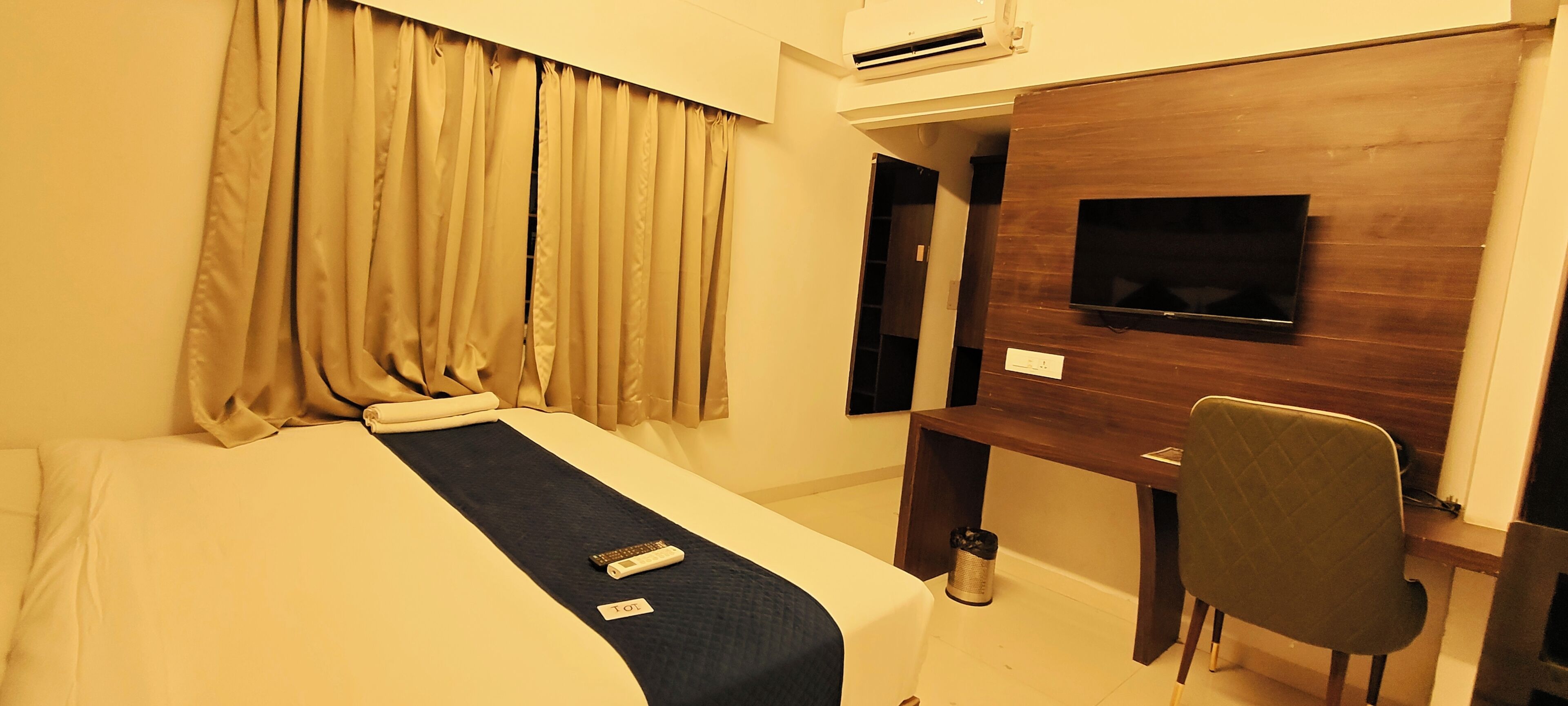 Une chambre d’hôtel équipée d’un lit, d’un bureau avec une chaise, d’une télévision et d’un appareil de climatisation.