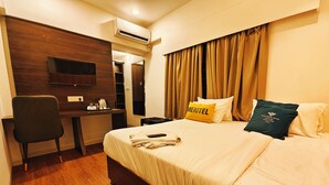 A hotel room with a bed, a desk, a chair, an air conditioner, and curtains. - Hotel Meritel Grande (Indore)