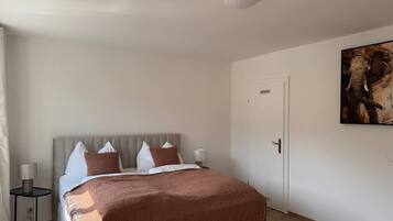 A bedroom with a bed, bedside tables, a door, and a wall-mounted artwork.
