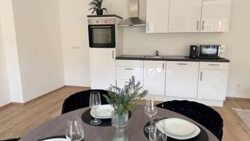 A modern kitchen with white cabinets, a built-in oven, and a microwave.