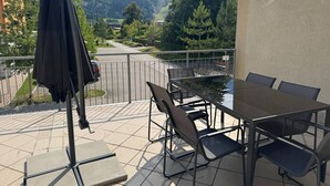 A terrace with a table and chairs, a black umbrella, and a view of mountains. - Faraway Homes Studio Mautern #8 (Mautern in Steiermark)