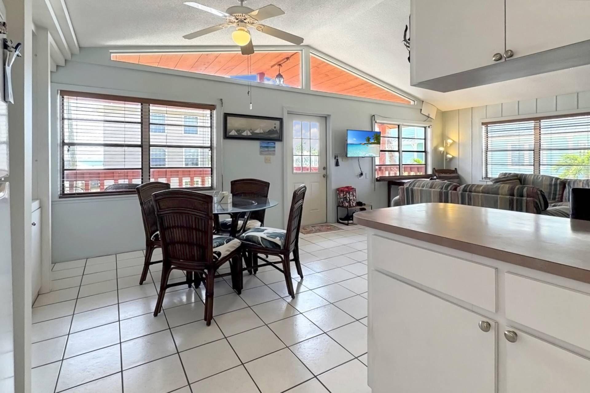 A dining area with a table and chairs, a kitchen with a counter, and a living area with a couch.