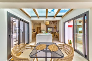 Ein modernes Interieur mit Glasdecke, Korbmöbeln und einem zentralen Eilandtisch.