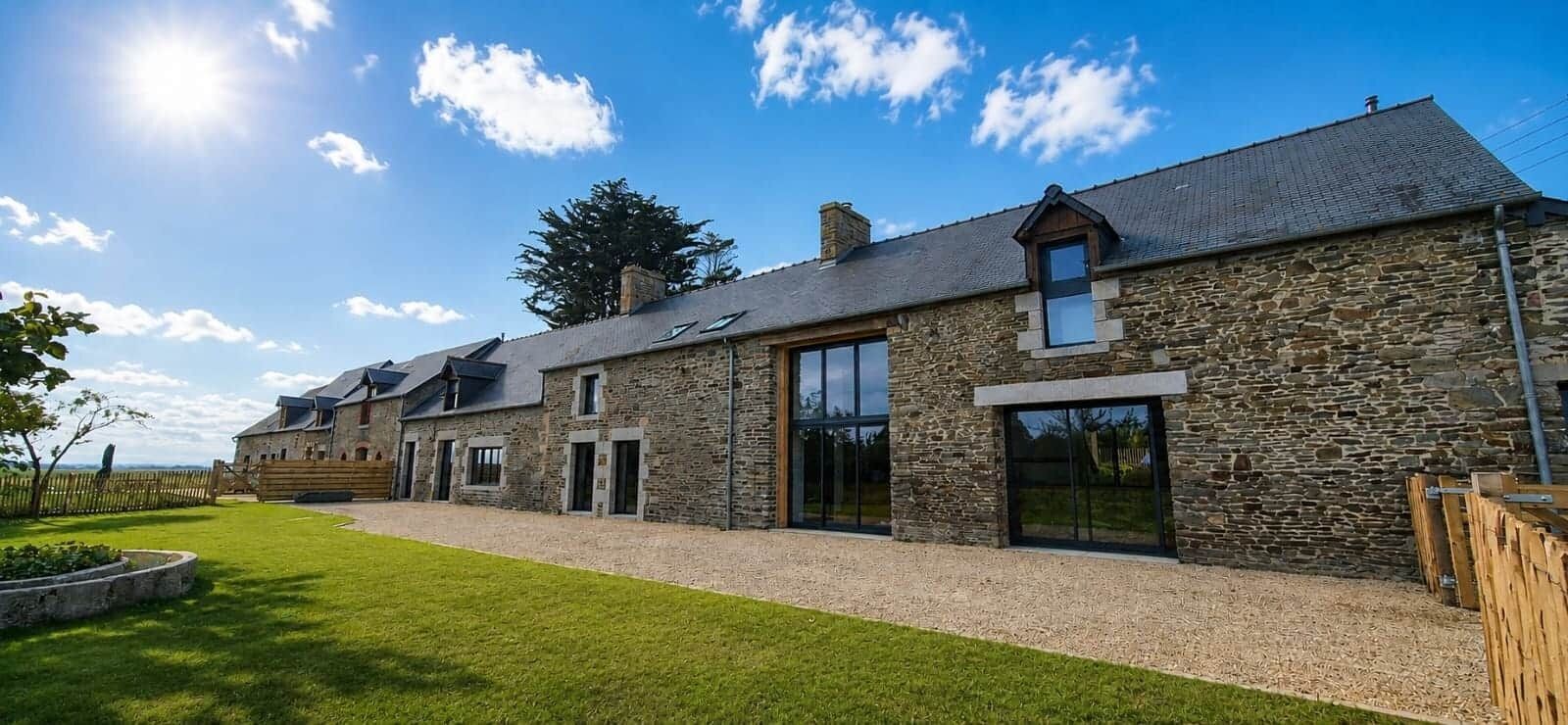 Un bâtiment en pierre doté de nombreuses fenêtres et portes, une allée pavée et une pelouse bien entretenue.