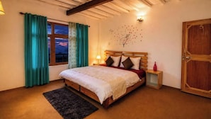 Ein Schlafzimmer mit einem hölzernen Bett, türkisfarbenen Vorhängen, einem Nachttisch, einer Wanduhr und einer Holztür.
