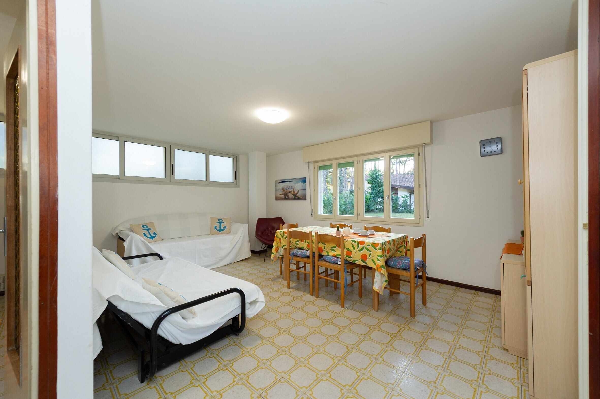 Una habitación con dos camas, una mesa de comedor con sillas, una ventana y una puerta.