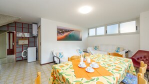 Un comedor con una mesa preparada para cuatro, un sofá y un cuadro en la pared.