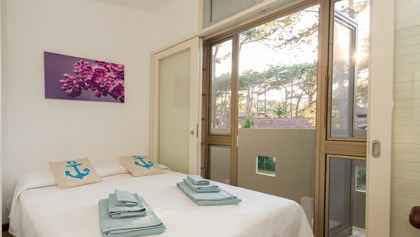 Una habitación de hotel con cama, almohadas, ventana y puerta.