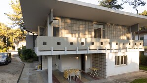 Un edificio moderno con techo plano, ventanas amplias y una zona de estar al aire libre cubierta.