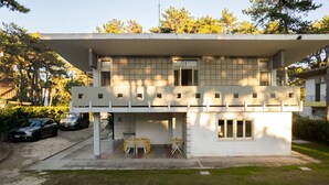 Un edificio moderno de dos pisos con techo plano, ventanas grandes y un área de estar exterior cubierta.