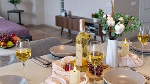 A dining setup with a bottle of wine, glasses, a bowl of fruit, and a candle on a table. - Modern Apartment with Library View (Minsk)