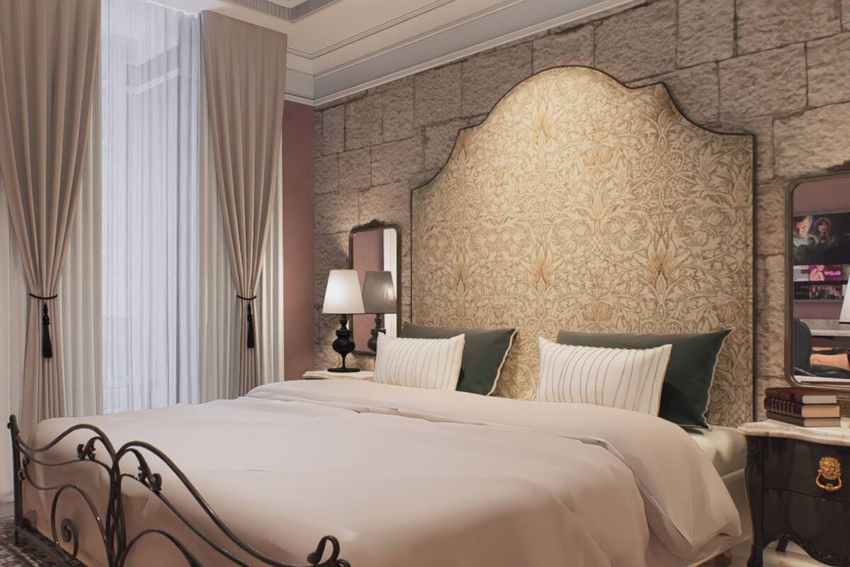 A hotel room with a bed, curtains, a nightstand, a lamp, a mirror, and a patterned wall.