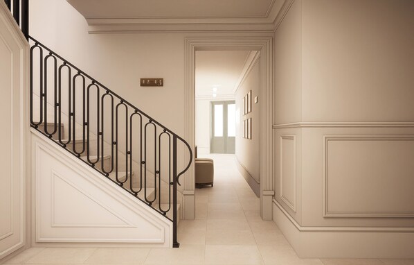A hallway with a staircase, a door at the end, and a number sign on the wall.