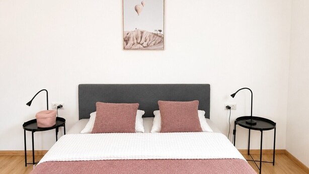 Ein Schlafzimmer mit einem Bett, zwei Nachttischen, einer Wandlampe und einem gerahmten Bild.