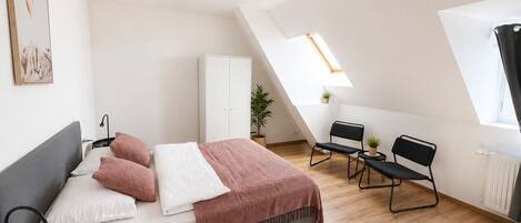 A modern bedroom with a bed, bedside tables, a desk, and a chair.
