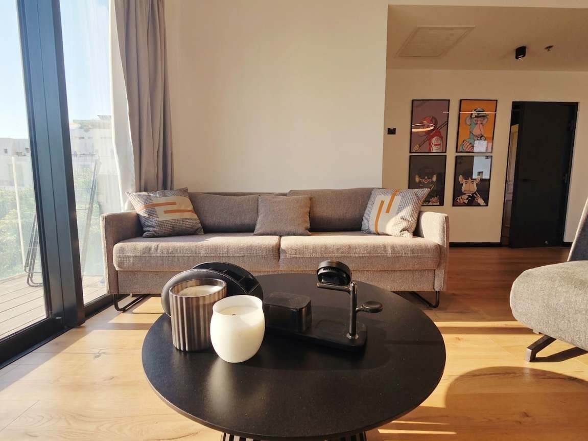 Un saló modern amb un sofà, una taula de centre rodona amb una espelma i un altaveu, i obra d'art a la paret.