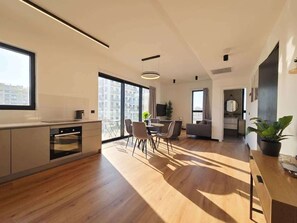 A modern kitchen with a dining area, large windows, and a view of buildings. - Herzl15 #TLV View- New 1BR & Mamad |By SweetyGuest (Tel Aviv-Yafo)
