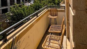 Ein Balkon mit Korbstühlen, Blick auf ein im Bau befindliches Gebäude und einen klaren Himmel.