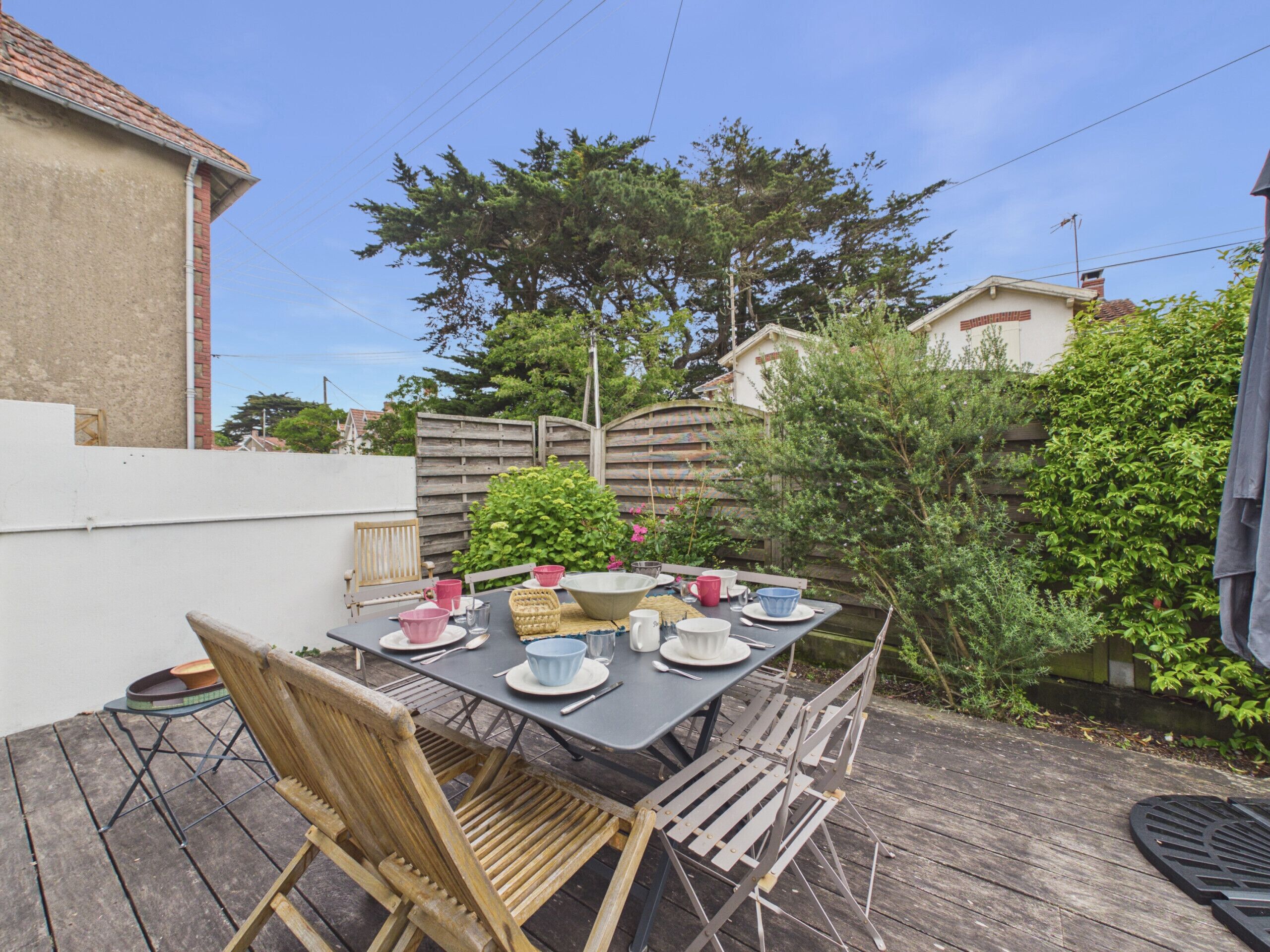 An outdoor dining area with a table set for four, surrounded by wooden chairs.