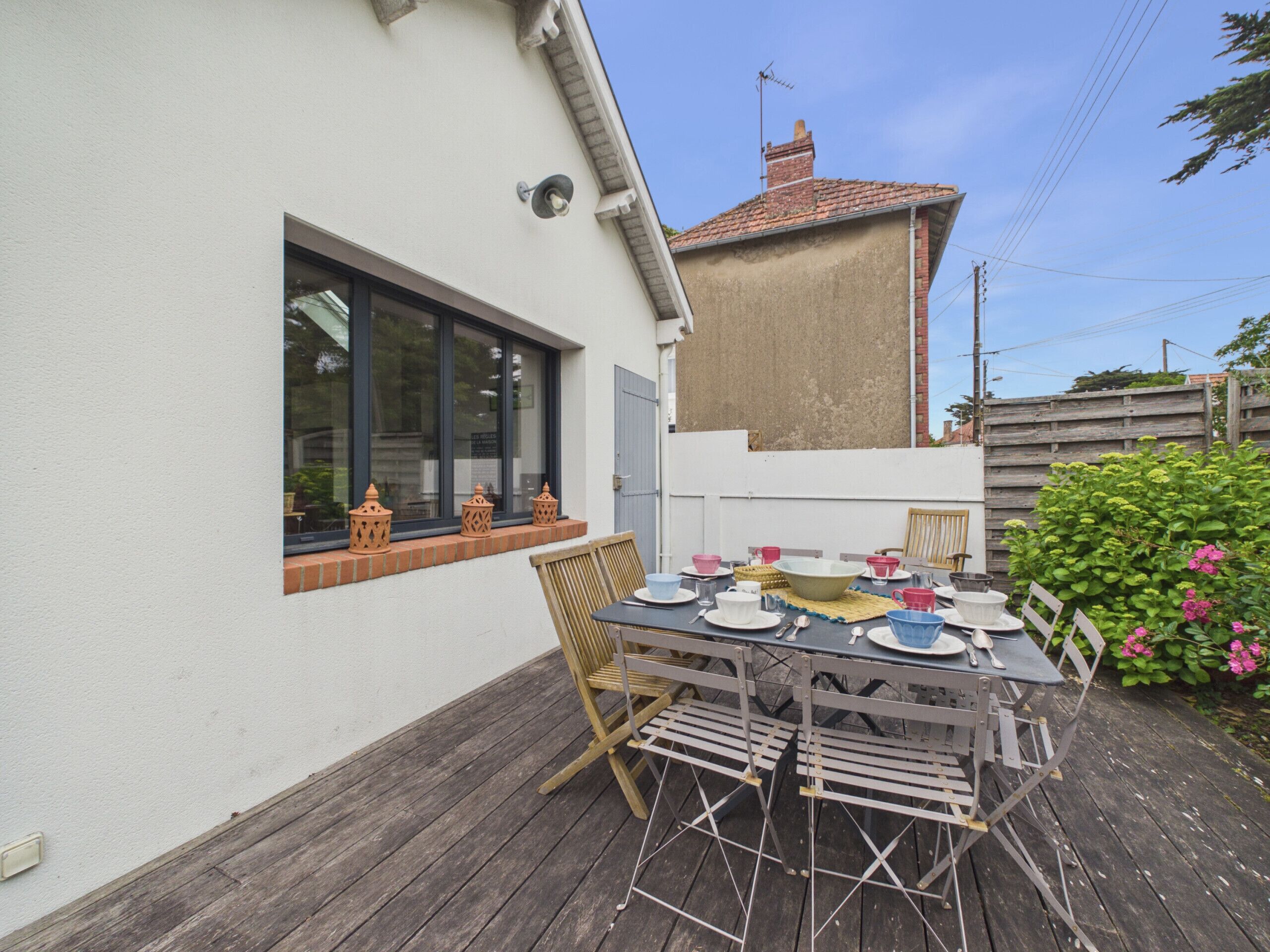 Un patio con una mesa lista para comer, una ventana decorada y un muro de ladrillo.
