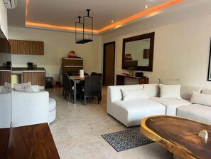 Ein modernes Wohnzimmer mit Sofa, Esstisch und Küchenbereich.