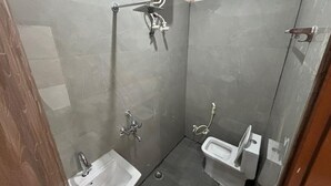 A small, enclosed shower area with a handheld showerhead, a wall-mounted faucet, and a separate sink. - Hotel Baldev Palace (Vrindavan)