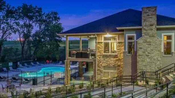 A house with a swimming pool, a covered patio, and a stone chimney. - Wooded Views | King Bed | No Stairs (West Des Moines)
