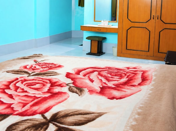 Une chambre avec une couvre-lit à motifs floraux, une armoire en bois et un mur bleu.