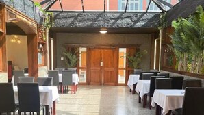 Un restaurant doté d’un plafond en verre, de portes en bois et de tables recouvertes de nappes blanches.