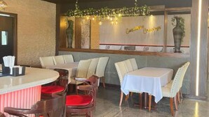 L’intérieur d’un restaurant, avec des tables rondes, des chaises rembourrées et un mur décoratif orné d’une enseigne.