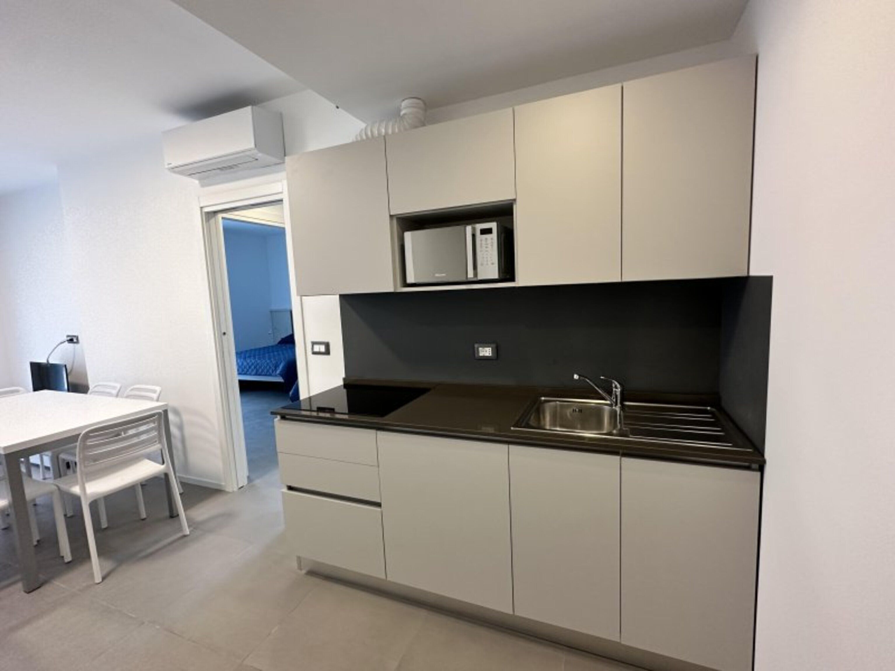 A modern kitchen with a black countertop, stainless steel sink, and white cabinetry.
