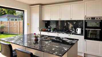 Een moderne keuken met een groot schiereiland, inbouwapparatuur en uitzicht op de achtertuin.